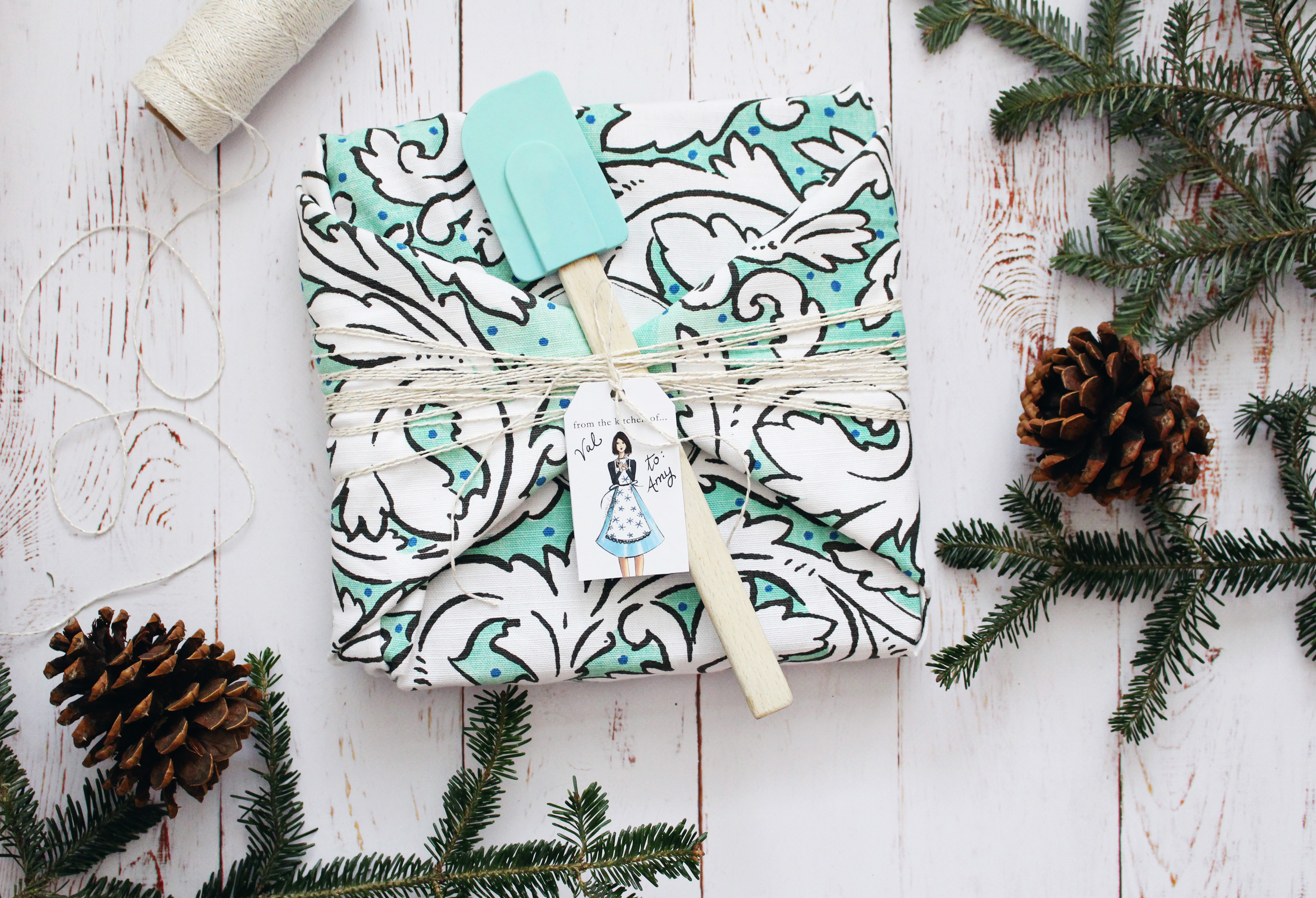 Wrap a kitchen themed gift in a tea towel, fasten with baker's twine, and include a spatula and pretty gift tag