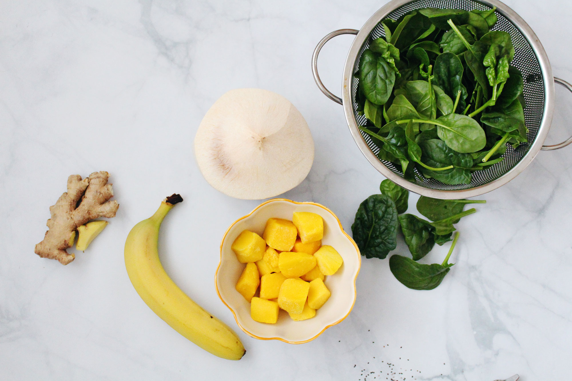 Ingredients for an amazing green smoothie: fresh ginger, banana, frozen mango, young coconut, spinach, and chia seeds